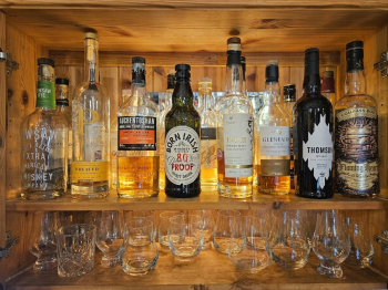 A shelf of the pub's whisky bottles above a row of tasting glasses
